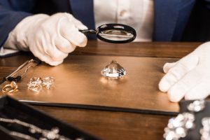 Cropped view of jewelry appraiser examining gemstone with magnifying glass