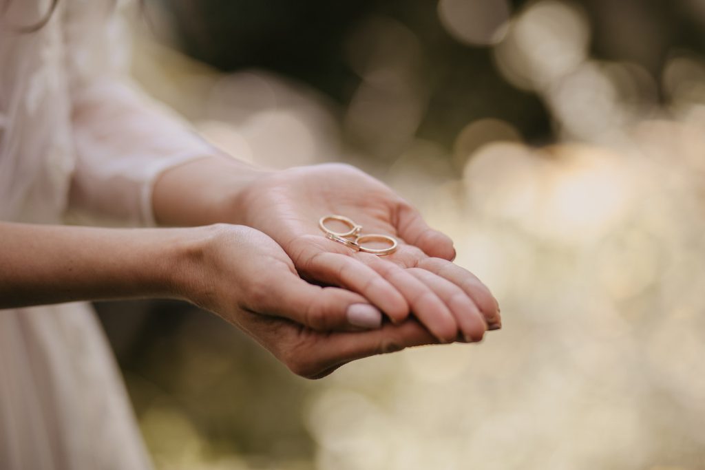 A close-up of a woman delicately holding two wedding rings.