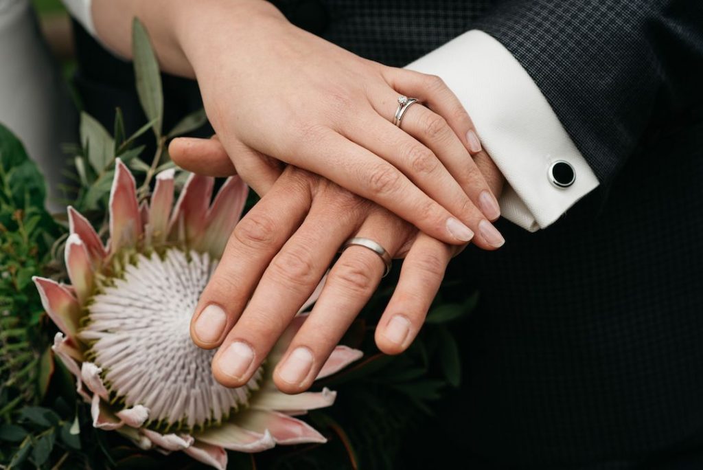 A closeup of the bride and groom holding hands with rings