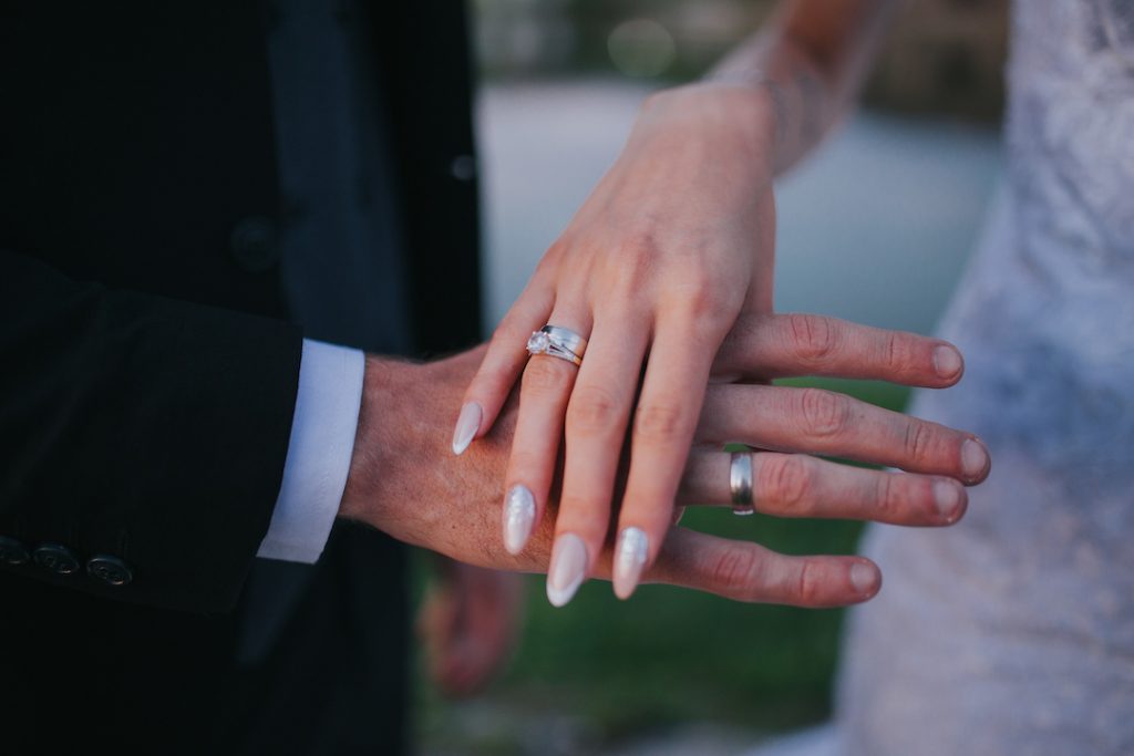 A closeup shot of a bride and bridegroom hands showing their wedding rings