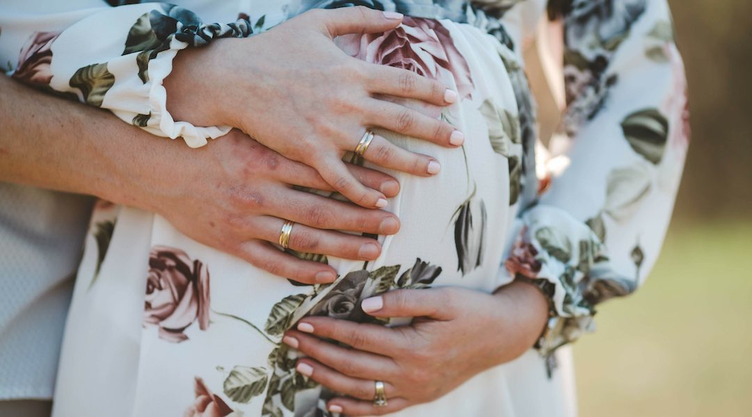 Closeup shot of a married couple waiting for their future baby wearing their rings