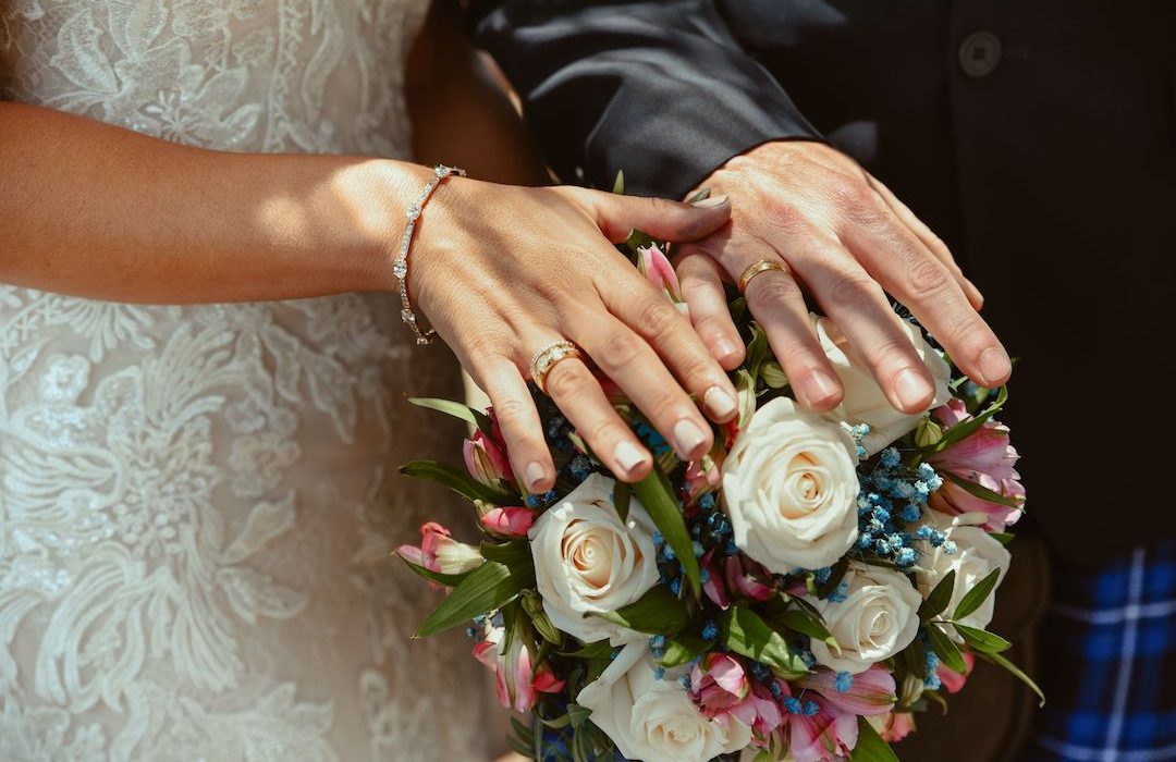 The couple wearing their wedding ring with bouquet