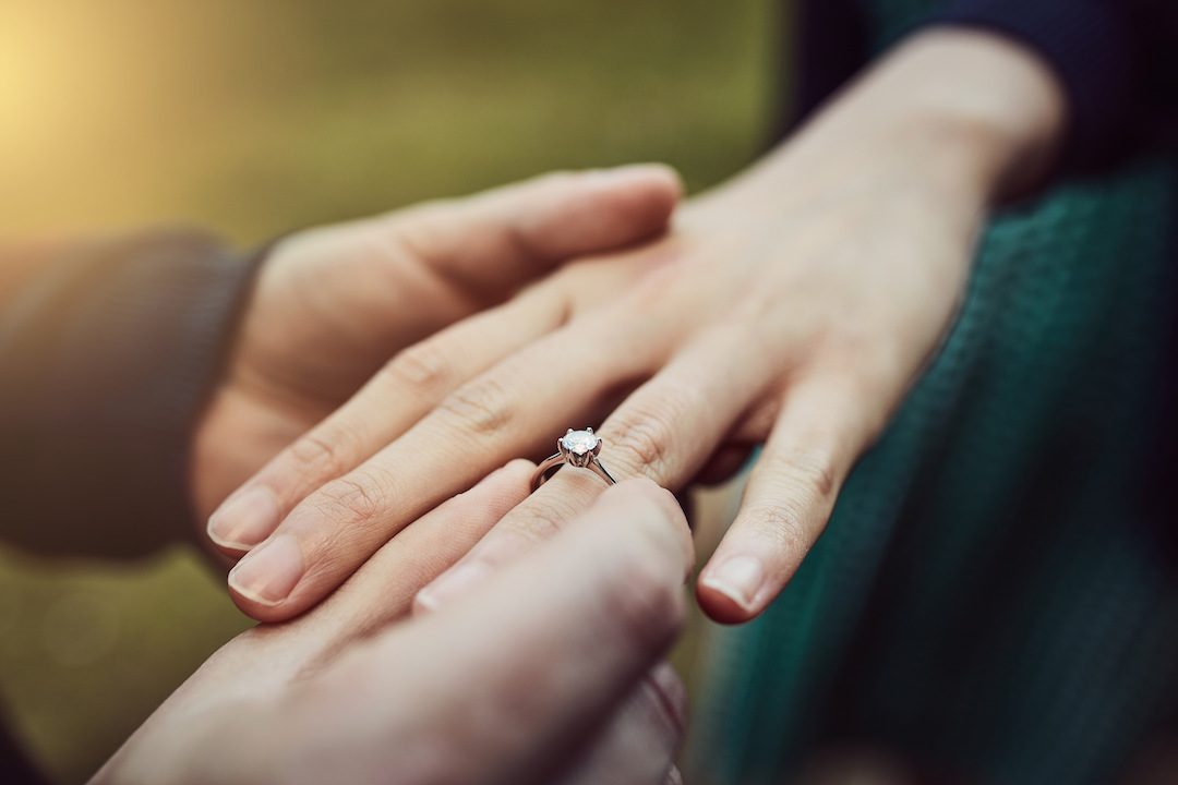 Cropped shot of a man putting an engagement ring onto his fiancees finger