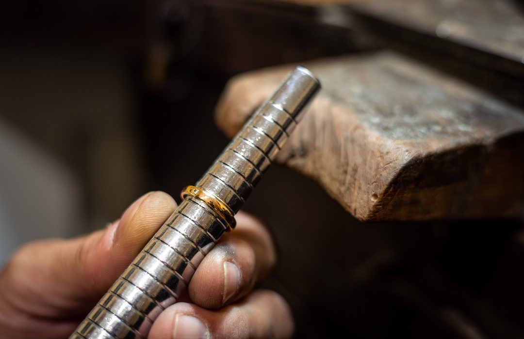 Jeweler hands measuring and checking ring size gauge mandrel. Goldsmith working repairing a gold jewel in his jewelry workshop.