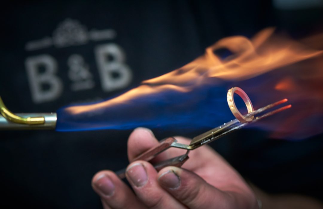 jeweller using torch and pliers to repair gold ring