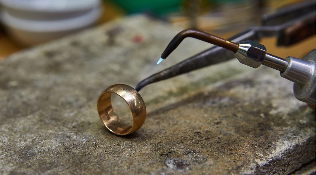 Jewelry production. The jeweler makes a gold ring.