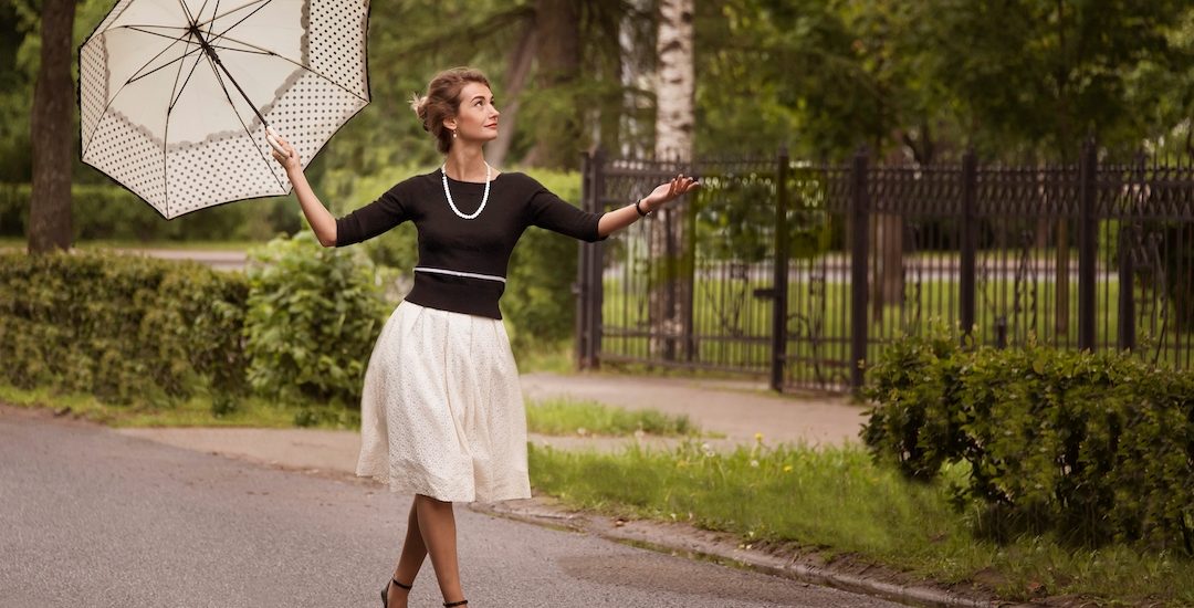 lady walking with umbrella wearing pearl necklace