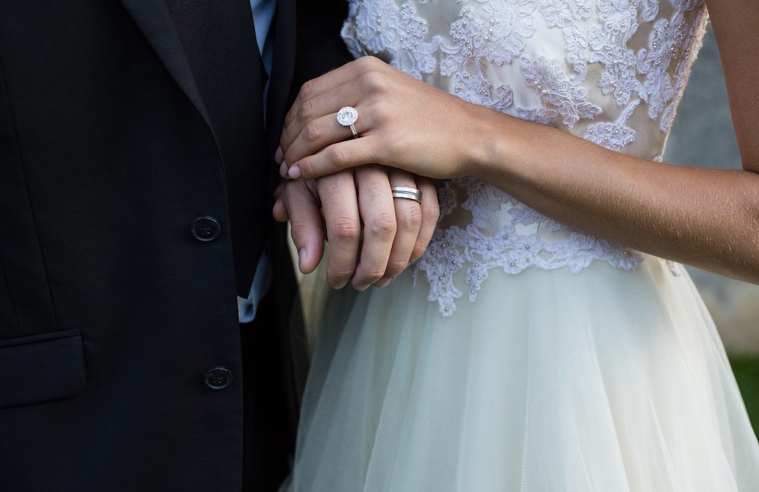 Mid-section of wedding couple holding hands