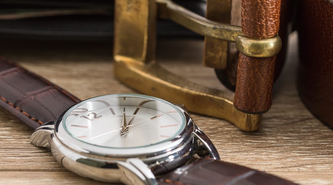Close up wristwatch and brown leather belt on wood table